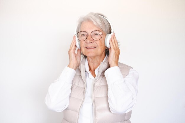 Mujer mayor sonriente y atractiva disfrutando de música escuchando canciones con auriculares de fondo blanco