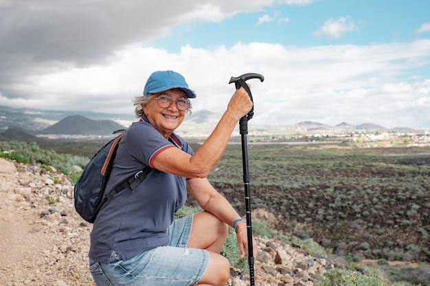 Mujer mayor sonriente en un día de caminata en un sendero al aire libre en una excursión en el campo Mujer caucásica relajada que disfruta de una aventura de viaje o una jubilación que lleva un estilo de vida saludable