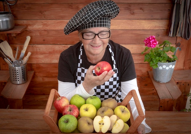 Foto una mujer mayor sonriente con frutas frescas en la canasta de pie en el mostrador de la cocina