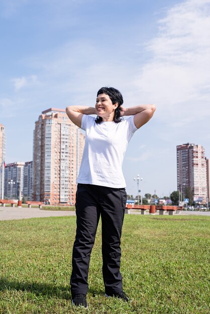 Mujer mayor sonriente haciendo calentamiento antes de entrenar al aire libre en el parque