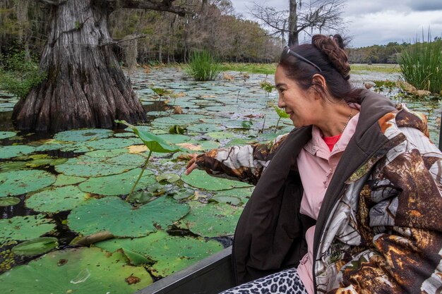 Foto una mujer mayor sonriente tocando una hoja mientras está sentada en un barco