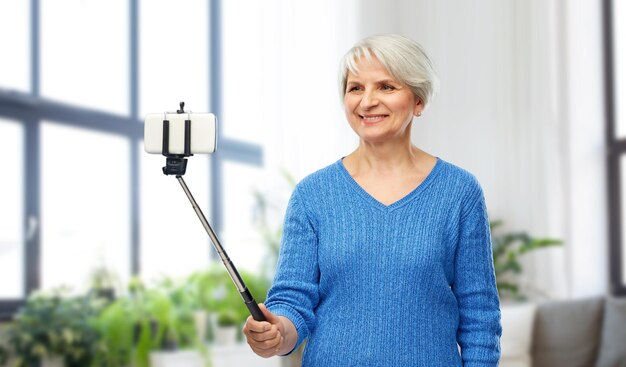 Una mujer mayor sonriente tomando una selfie con su teléfono inteligente