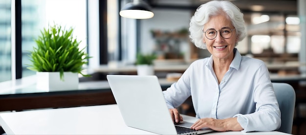 Una mujer mayor sonriente trabajando en una computadora portátil en la oficina