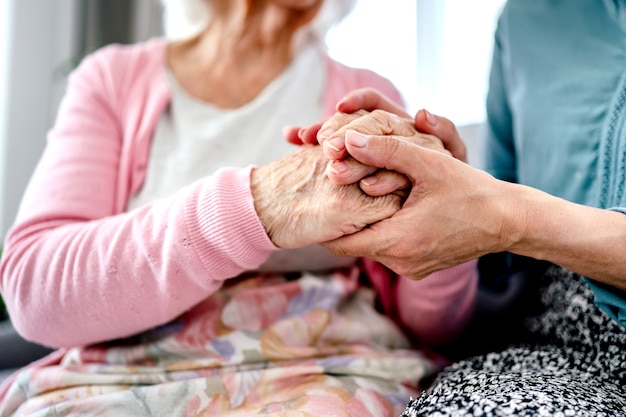 Mujer mayor y su hija cogidos de la mano. Abuela con nieta momentos familiares juntos