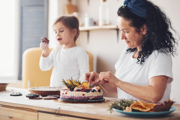 Mujer mayor con su nieta preparando pastel dietético en la cocina