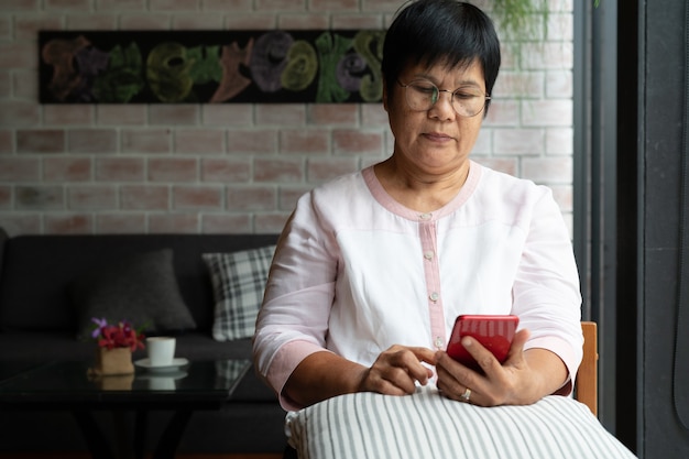 Foto mujer mayor con teléfono móvil mientras está sentado en el sofá en casa