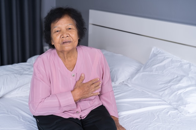 mujer mayor teniendo problema de corazón en una cama