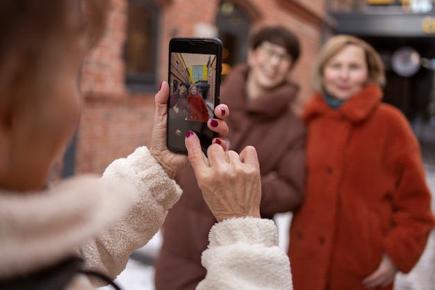 Foto mujer mayor tomando una foto de sus amigos mientras toma un café al aire libre