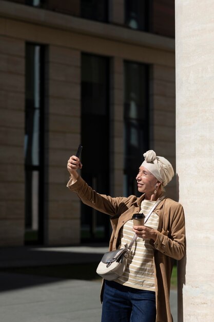 Mujer mayor tomando selfie con smartphone al aire libre en la ciudad
