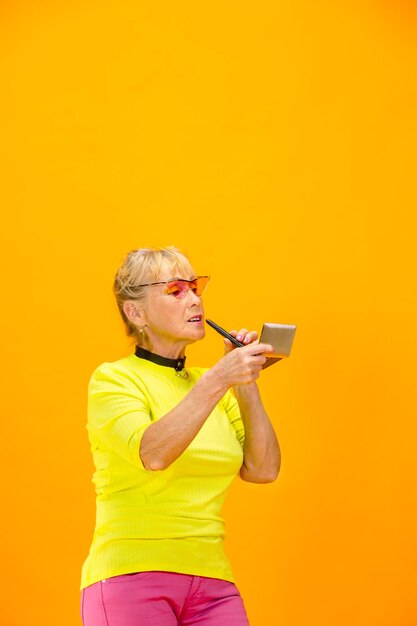 Mujer mayor en traje ultra moderno aislado sobre fondo naranja brillante