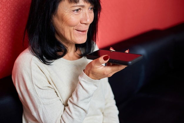 La mujer mayor usa el altavoz de la llamada del chat de voz del teléfono móvil