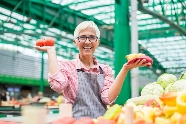 Mujer mayor vende verduras en el mercado