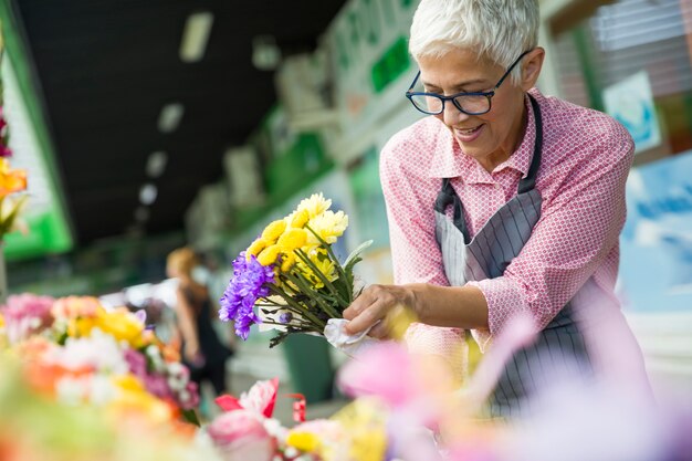 Mujer mayor venta de flores en el mercado de flores local