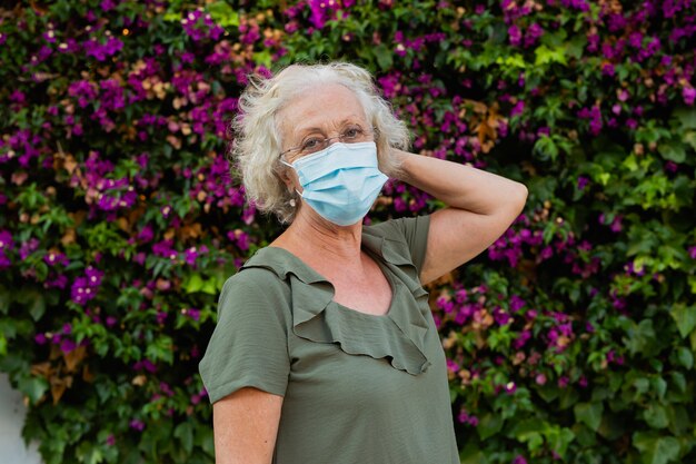 Mujer mayor vistiendo una mascarilla quirúrgica azul en la calle