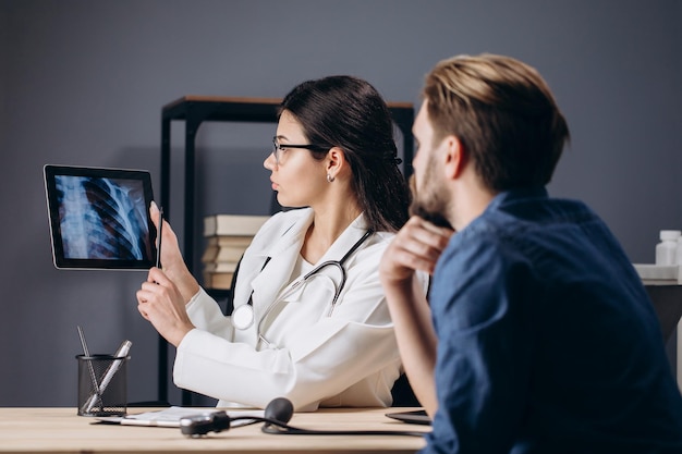 Mujer MD usando tableta para mostrar rayos X de tórax