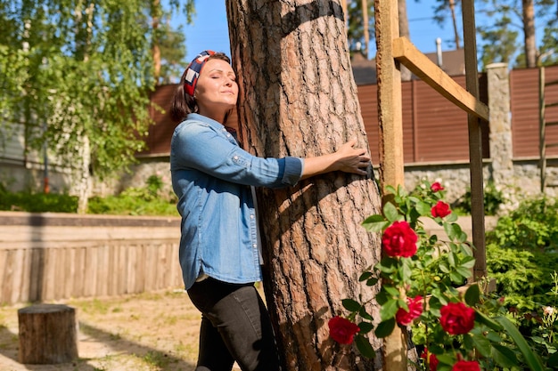 Mujer de mediana edad abrazando un árbol de energía de la naturaleza