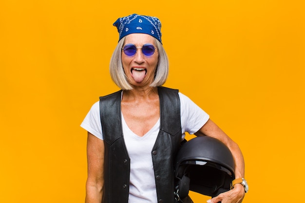 Foto mujer de mediana edad con actitud alegre, despreocupada y rebelde, bromeando y sacando la lengua, divirtiéndose