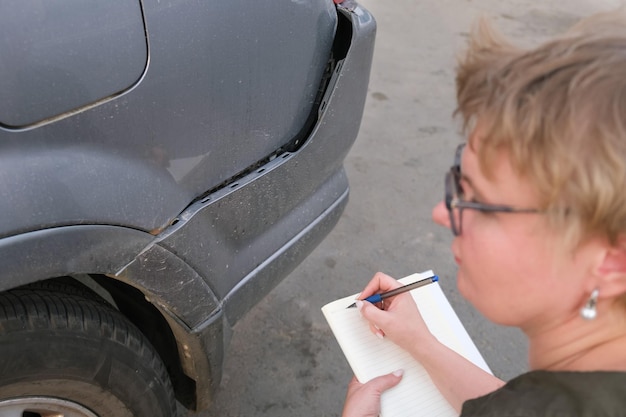 Una mujer de mediana edad agente de seguros realiza una inspección previa al seguro del automóvil