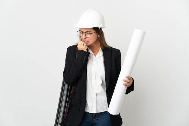 Mujer de mediana edad arquitecto con casco y sosteniendo planos sobre pared aislada que tiene dudas