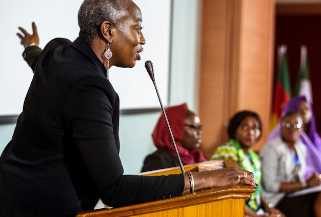 Mujer de mediana edad de ascendencia africana hablando en un micrófono