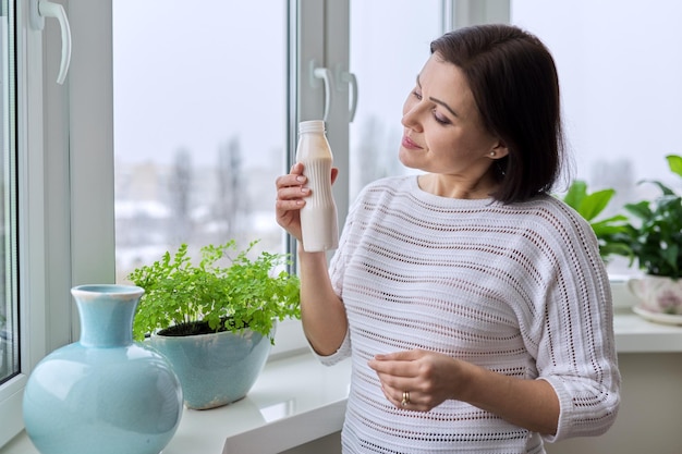 Mujer de mediana edad bebiendo leche de yogur de productos lácteos en botella