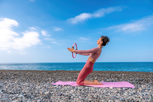 Mujer de mediana edad bien parecido con cabello negro haciendo pilates con el anillo en la estera de yoga cerca de la