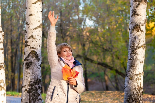 Una mujer de mediana edad camina en un parque de otoño