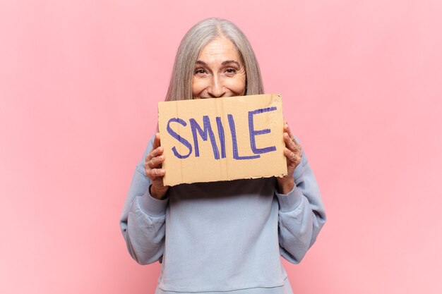 Mujer de mediana edad con un cartel con la sonrisa de texto