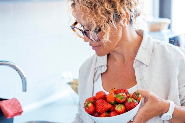 Una mujer de mediana edad en casa con un plato fresco de fresas rojas frutas de temporada Concepto de pérdida de peso y conteo de déficit calórico Comer dieta natural personas sanas estilo de vida femenino Frutas de fresas