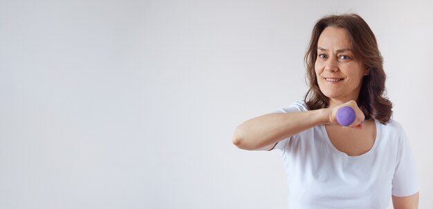 Mujer de mediana edad en casa trabajando con pesas