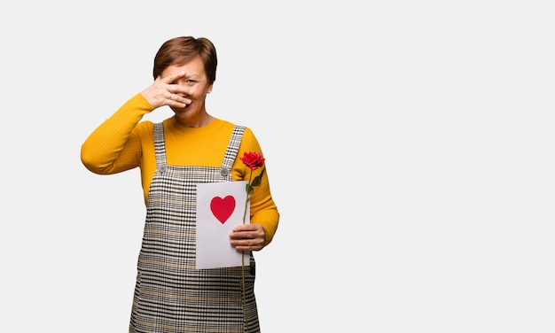 Mujer de mediana edad celebrando el día de San Valentín avergonzada y riendo al mismo tiempo