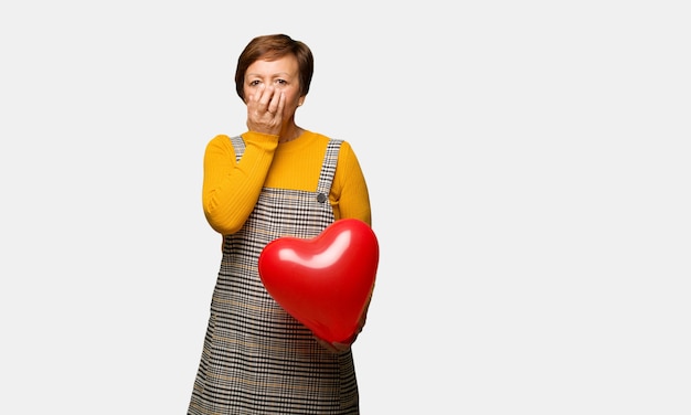 Mujer de mediana edad celebrando el día de san valentín muy asustada y con miedo escondido