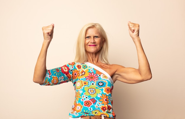 Mujer de mediana edad celebrando un éxito increíble como una ganadora, luciendo emocionada y feliz diciendo ¡toma eso!