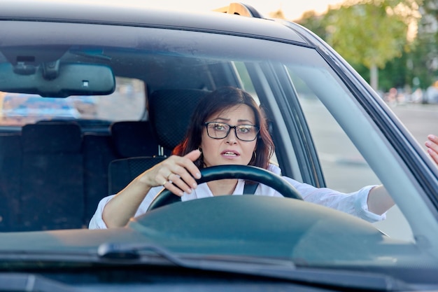 Mujer de mediana edad conductora con gafas mujer conduciendo un coche