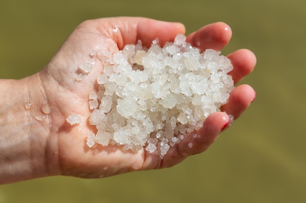Mujer de mediana edad con cristales de sal en la mano del Mar Muerto