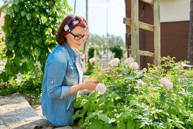 Mujer de mediana edad disfrutando de la belleza de la naturaleza primaveral del rosal