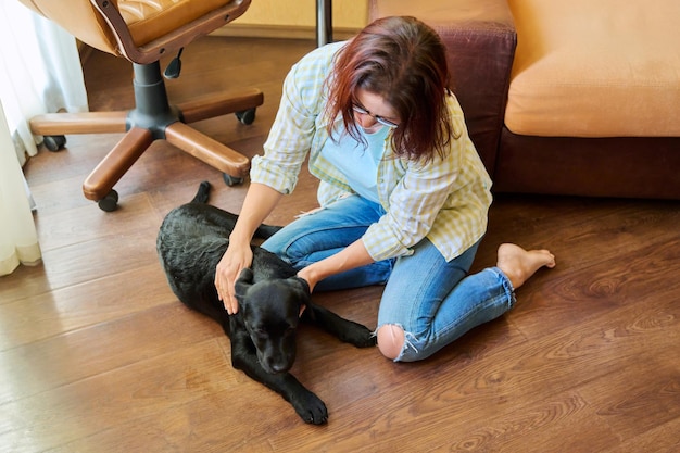 Mujer de mediana edad dueña junto con un perro joven en casa