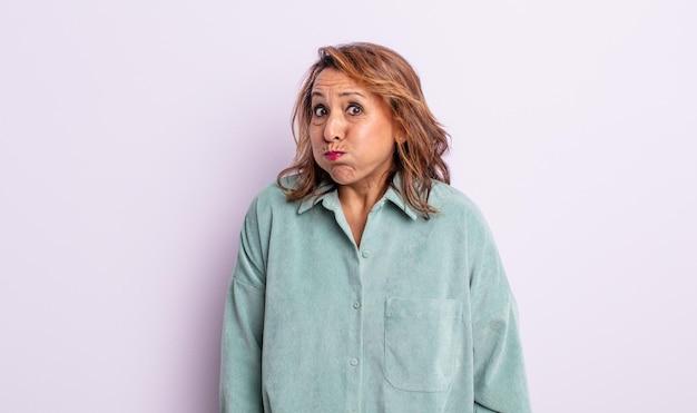 Mujer de mediana edad con una expresión tonta, loca y sorprendida, mejillas hinchadas, sintiéndose rellena, gorda y llena de comida.