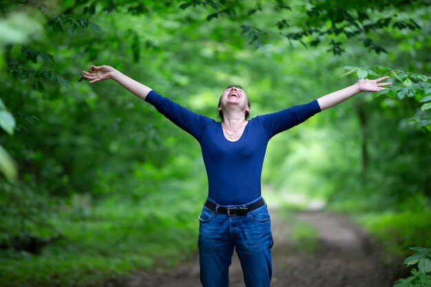 Mujer de mediana edad feliz extendió sus brazos en el bosque