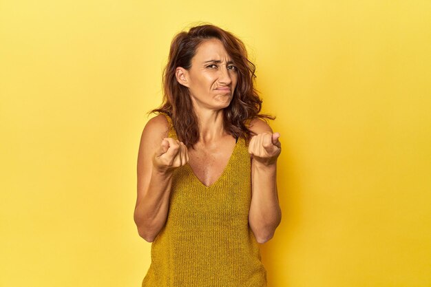 Mujer de mediana edad con un fondo amarillo que muestra que no tiene dinero