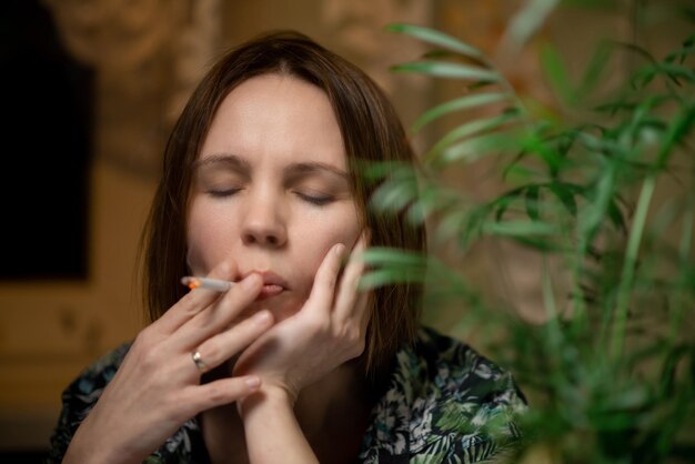 Foto una mujer de mediana edad fuma rodeada de plantas verdes concepto de relajación por agotamiento por fatiga