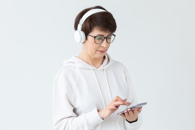 Mujer de mediana edad con gafas y un suéter se sienta en una silla y escucha su radio en línea favorita