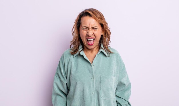 Mujer de mediana edad gritando agresivamente luciendo muy enojada frustrada indignada o molesta gritando no
