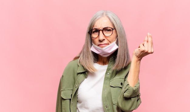 Mujer de mediana edad haciendo capice o gesto de dinero, ¡diciéndole que pague sus deudas!