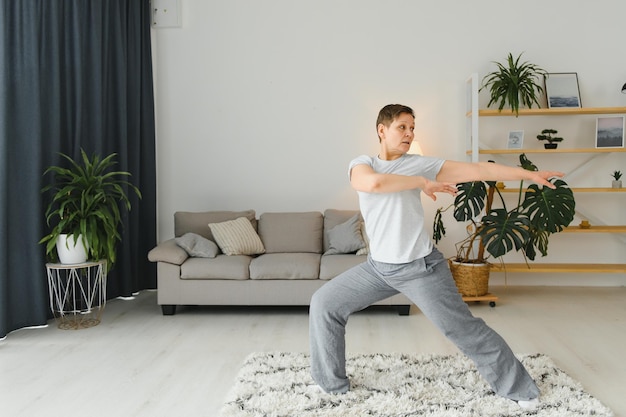 Mujer de mediana edad haciendo yoga en casa para estirar y estar saludable