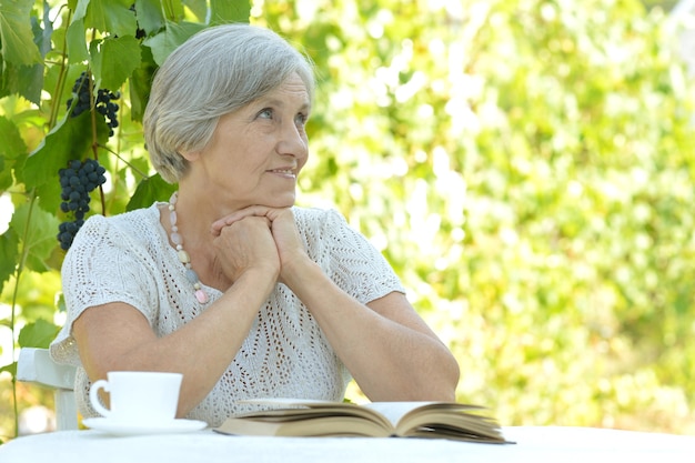 Mujer de mediana edad leyendo un libro y bebiendo té