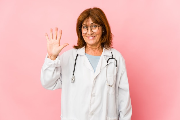 Mujer de mediana edad médico caucásico aislado sonriendo alegre mostrando el número cinco con los dedos.