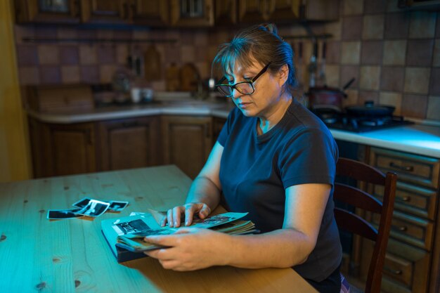 Mujer de mediana edad mirando el álbum de fotos familiar Nostalgia tristeza recuerdos en el concepto de mediana edad