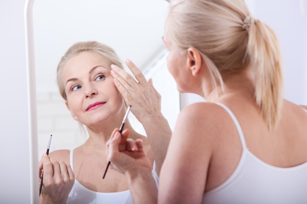 Mujer de mediana edad mirando arrugas en el espejo. Enfoque selectivo