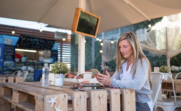 Mujer de mediana edad mirando el móvil en una cafetería.